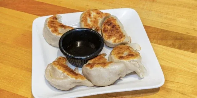 Potstickers with dipping sauce on a white plate at Mo’s Chinese #2